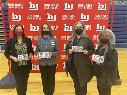 Principal and PTA leaders holding placards in front of Bob Jones High School banner